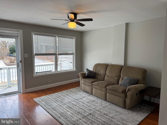 living area with a wealth of natural light, ceiling fan, baseboards, and wood finished floors