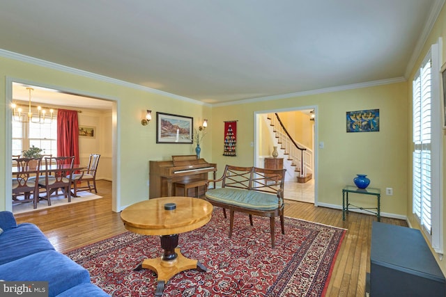 living room featuring crown molding, baseboards, stairs, hardwood / wood-style floors, and an inviting chandelier