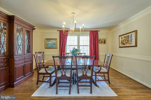 dining room featuring dark wood finished floors, baseboards, an inviting chandelier, and ornamental molding