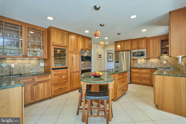 kitchen featuring a sink, stainless steel appliances, brown cabinetry, and light tile patterned floors