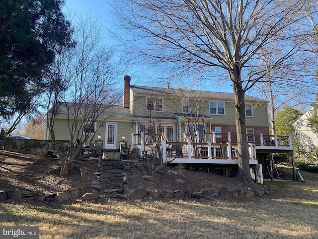 back of house with brick siding, a chimney, and a deck