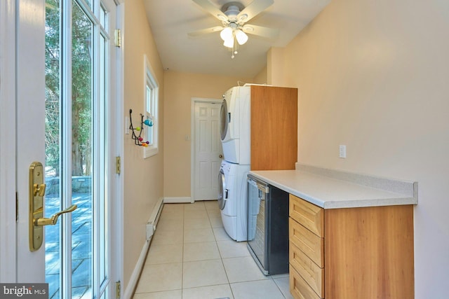 washroom featuring a baseboard heating unit, light tile patterned floors, stacked washer / drying machine, baseboards, and laundry area