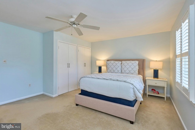 carpeted bedroom with baseboards, two closets, and ceiling fan