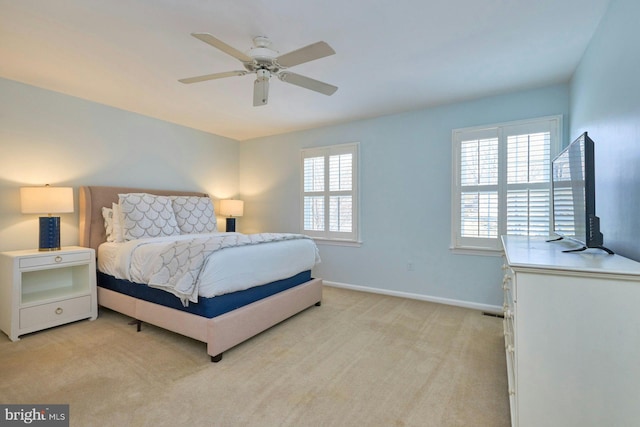 bedroom with a ceiling fan, baseboards, and light carpet