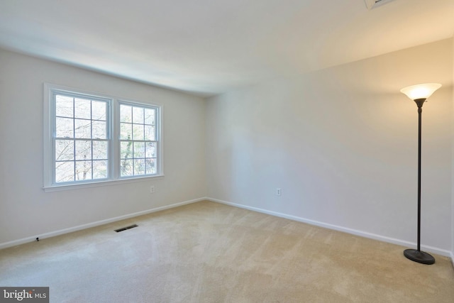 empty room featuring visible vents, light colored carpet, and baseboards