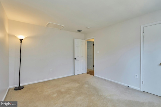 unfurnished room with attic access, baseboards, visible vents, and carpet floors