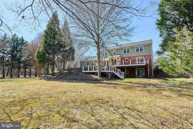 rear view of house featuring a yard, brick siding, stairs, and a deck