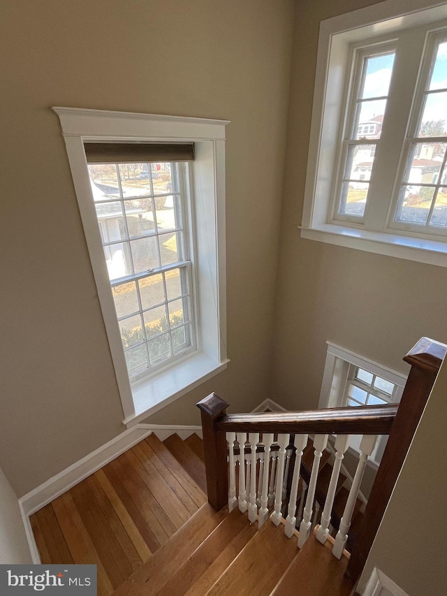 staircase with a healthy amount of sunlight, baseboards, and wood finished floors