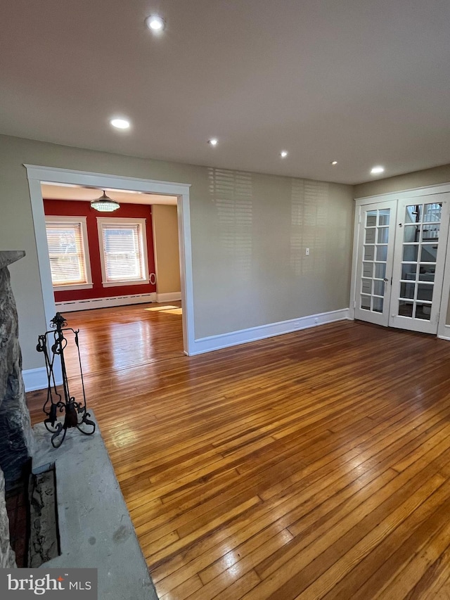 unfurnished living room featuring a baseboard heating unit, recessed lighting, baseboards, and hardwood / wood-style floors