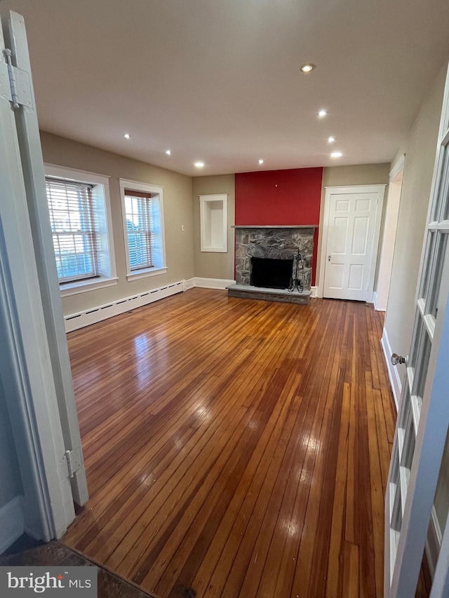 unfurnished living room featuring wood-type flooring, a fireplace, baseboard heating, and recessed lighting