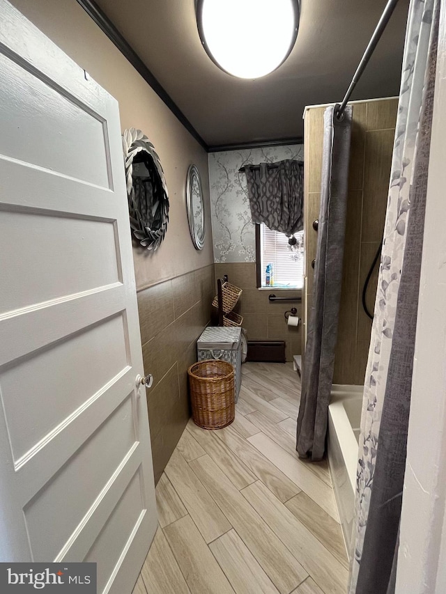 full bath featuring shower / tub combo, a wainscoted wall, wood tiled floor, a baseboard heating unit, and tile walls