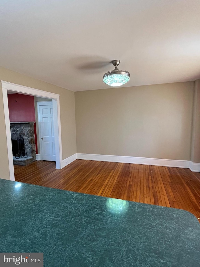 spare room with a fireplace, wood finished floors, and baseboards