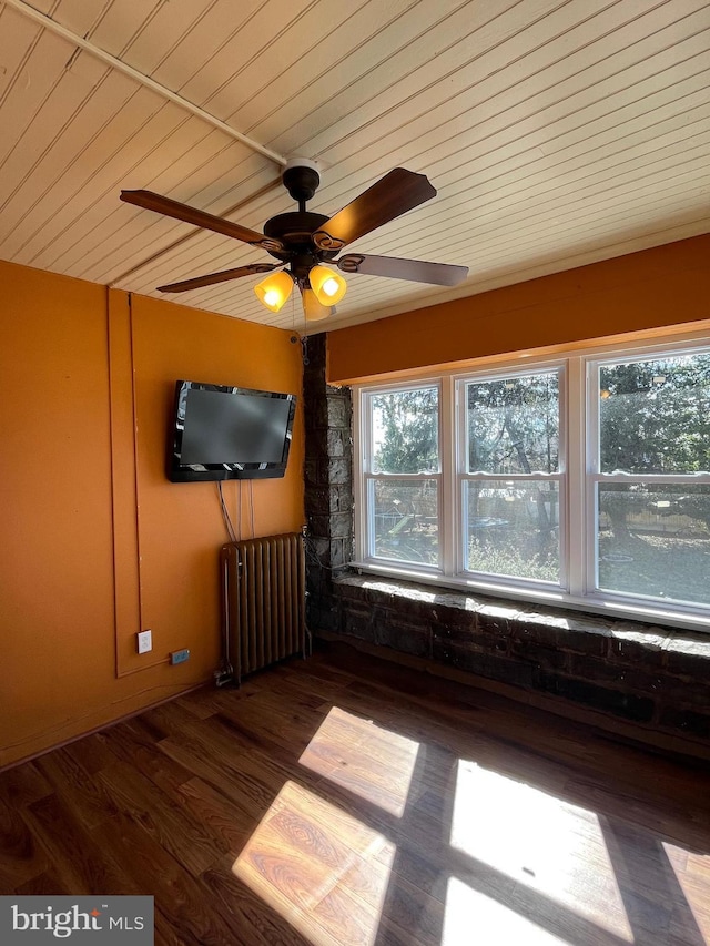 empty room featuring wood ceiling, radiator heating unit, and wood finished floors