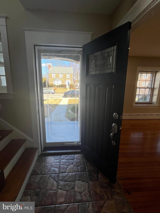 entryway featuring a baseboard heating unit, stairs, and baseboards