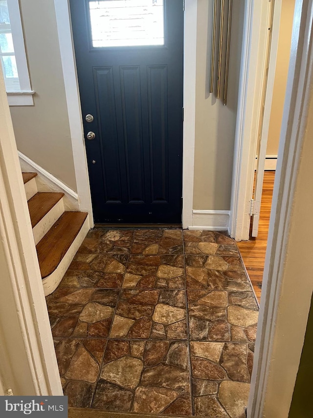 entryway featuring stairs, baseboard heating, and baseboards