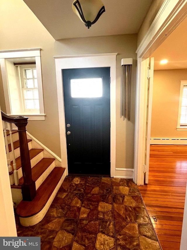 entryway featuring baseboards, plenty of natural light, stairway, and wood finished floors