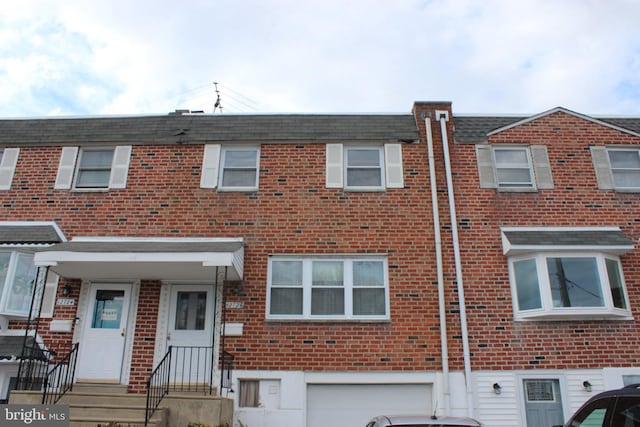 view of property featuring an attached garage and brick siding