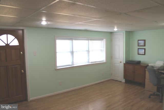 interior space featuring a paneled ceiling, baseboards, and wood finished floors