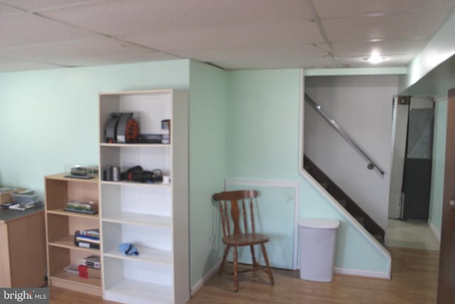 interior space with a drop ceiling, stairs, and wood finished floors