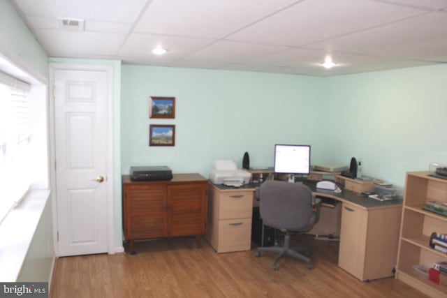 office space with a drop ceiling and light wood finished floors