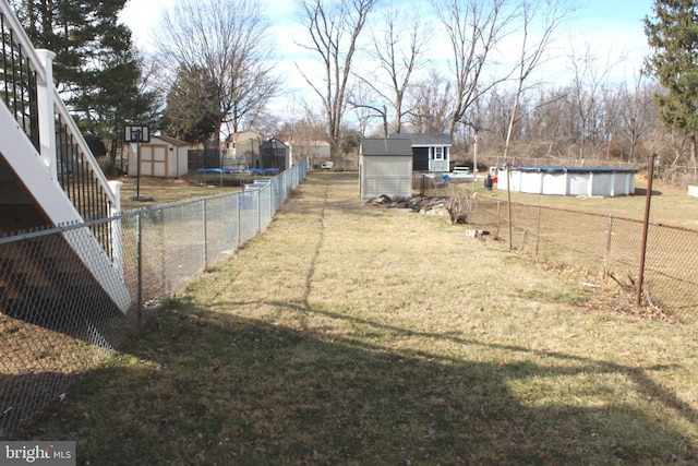 view of yard featuring a fenced in pool, an outbuilding, a storage shed, and fence