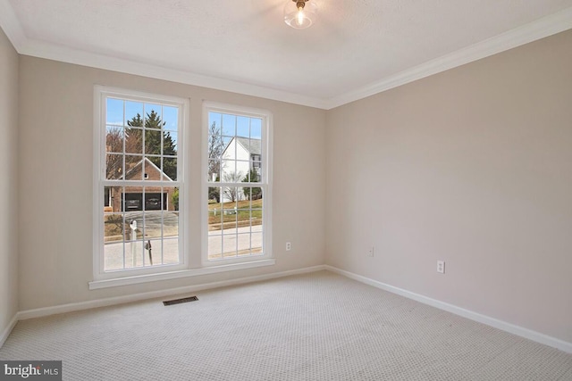 unfurnished room with crown molding, carpet, baseboards, and visible vents