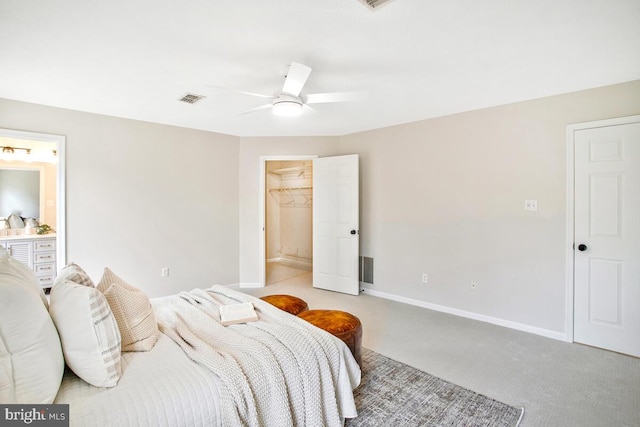 carpeted bedroom featuring baseboards, visible vents, ensuite bath, ceiling fan, and a spacious closet