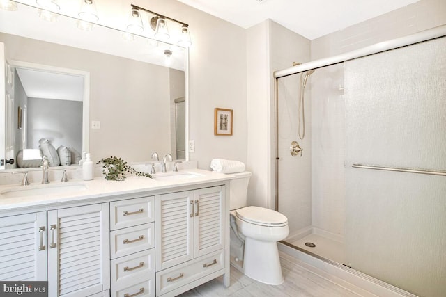 ensuite bathroom with double vanity, a stall shower, toilet, and a sink