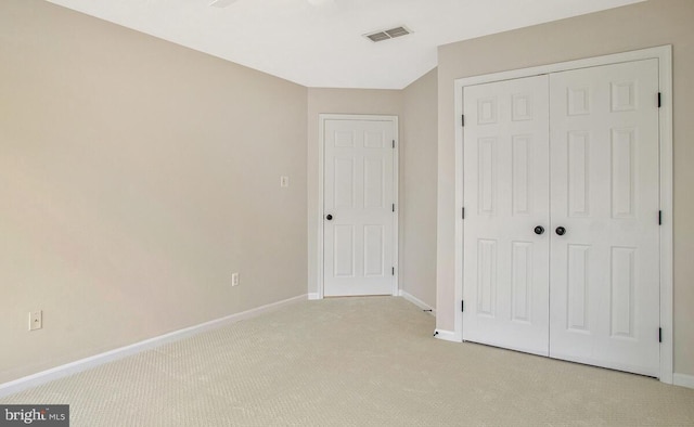 unfurnished bedroom with visible vents, baseboards, a closet, and light carpet