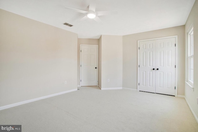 unfurnished bedroom featuring visible vents, a ceiling fan, a closet, baseboards, and light colored carpet