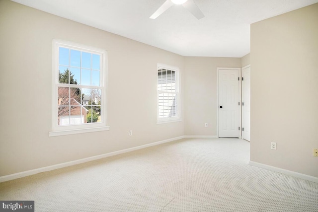 spare room featuring a ceiling fan, a healthy amount of sunlight, baseboards, and light carpet