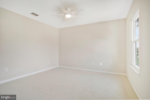 spare room featuring baseboards, visible vents, plenty of natural light, and light carpet