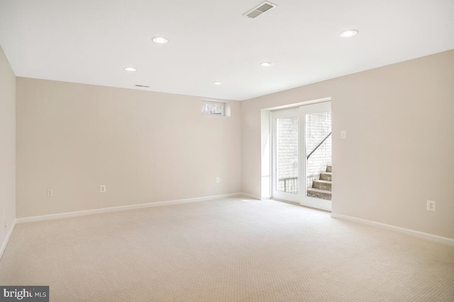 spare room featuring light carpet, visible vents, stairs, and baseboards