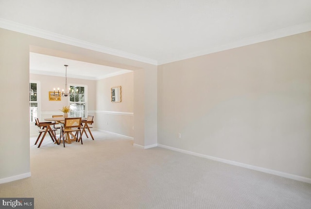 dining room featuring light colored carpet, an inviting chandelier, baseboards, and ornamental molding