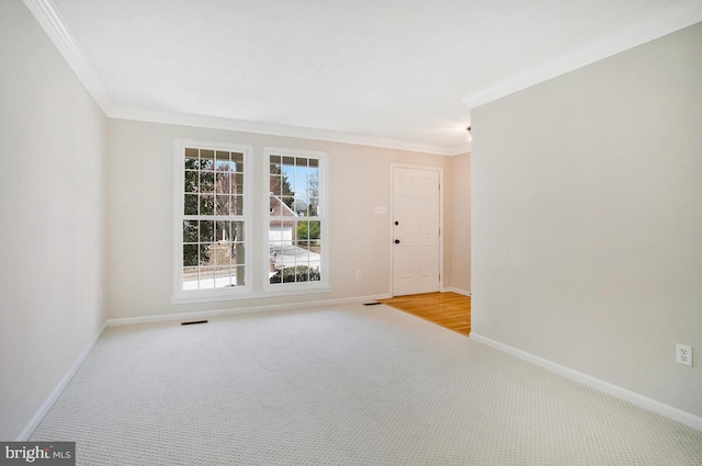 unfurnished room with visible vents, baseboards, ornamental molding, and carpet flooring