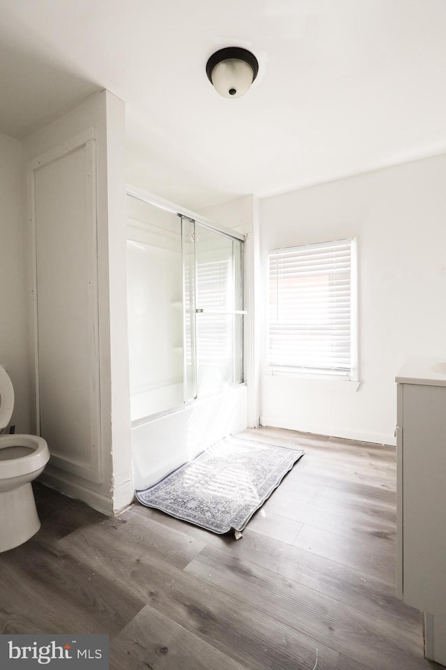 full bath with vanity, toilet, wood finished floors, and bath / shower combo with glass door