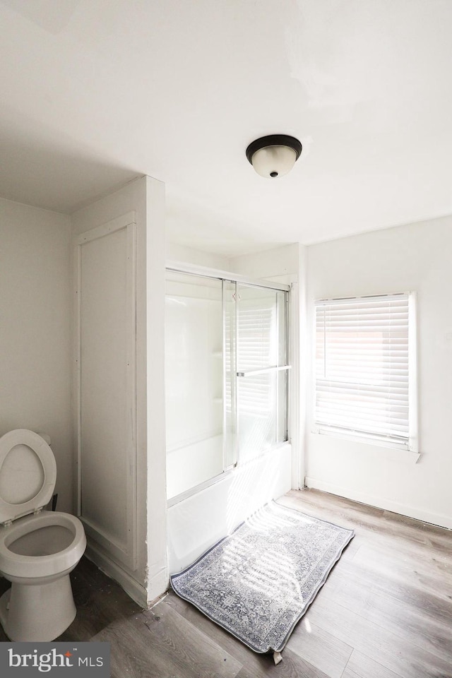 full bathroom with baseboards, shower / bath combination with glass door, and wood finished floors