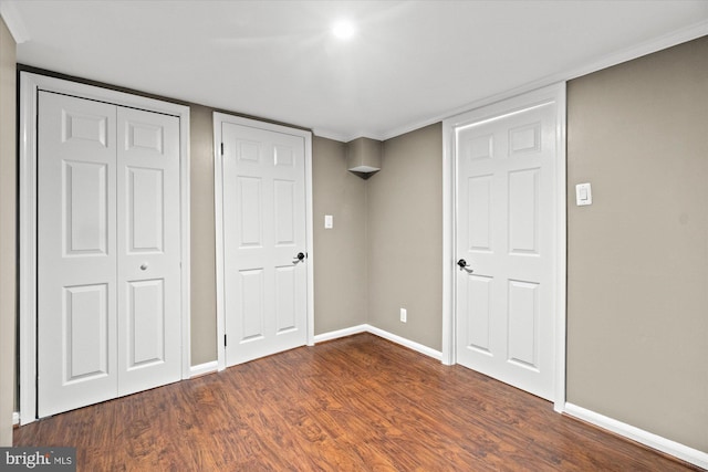 unfurnished bedroom featuring baseboards, dark wood-style flooring, and a closet