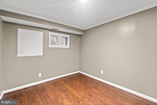 spare room featuring visible vents, baseboards, wood finished floors, and crown molding