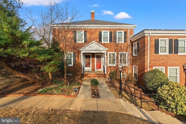 view of front of property featuring brick siding and a chimney