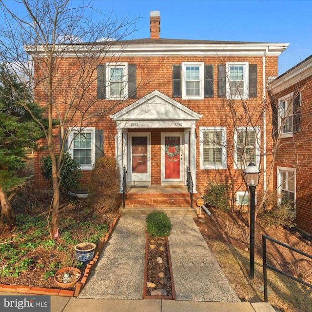 view of front of home featuring brick siding and a chimney