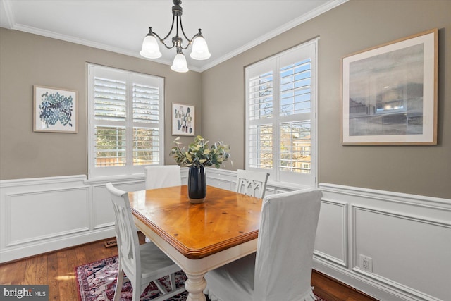 dining room with an inviting chandelier, dark wood-type flooring, a wainscoted wall, and ornamental molding