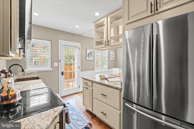 kitchen featuring freestanding refrigerator, a sink, light wood-style floors, cream cabinets, and black electric range oven