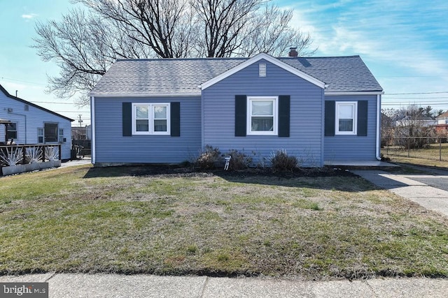 view of front of home with a chimney, roof with shingles, a front lawn, and fence