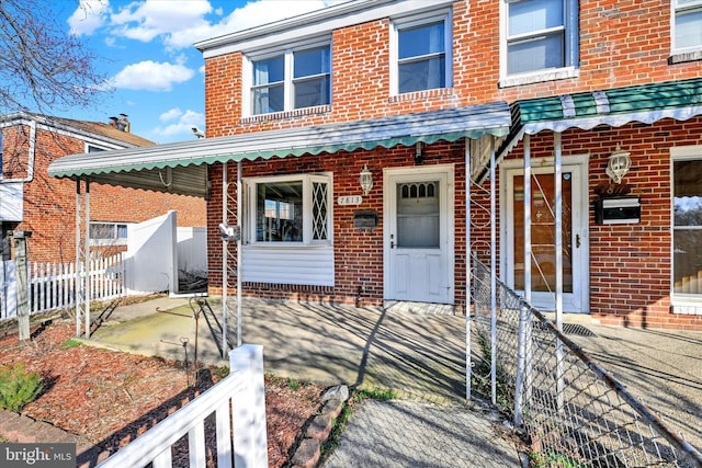 view of front of property featuring fence and brick siding