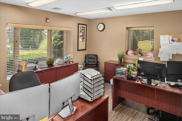 home office with visible vents, a healthy amount of sunlight, and wood finished floors