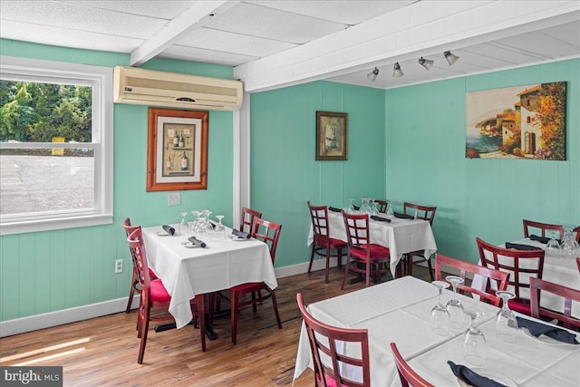 dining area featuring wood finished floors, baseboards, and a wall mounted AC