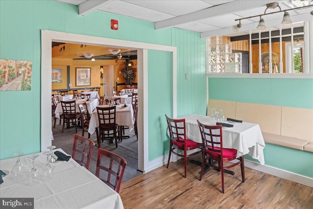 dining space with beam ceiling and wood finished floors