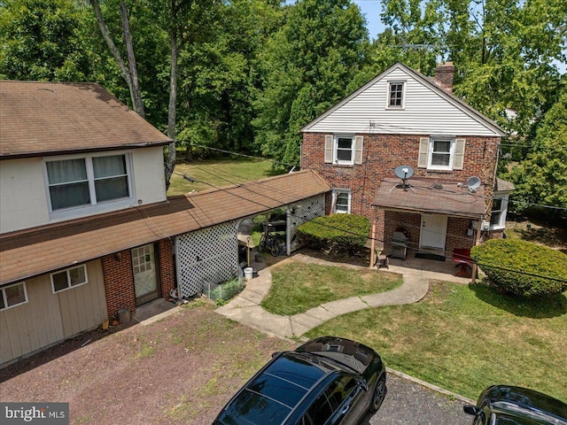 view of front of home with brick siding, a chimney, and a front yard