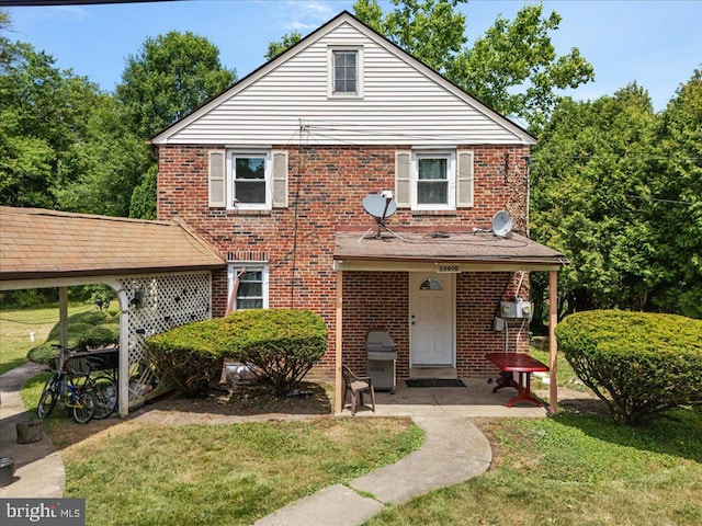 traditional-style house featuring brick siding, a patio area, and a front lawn